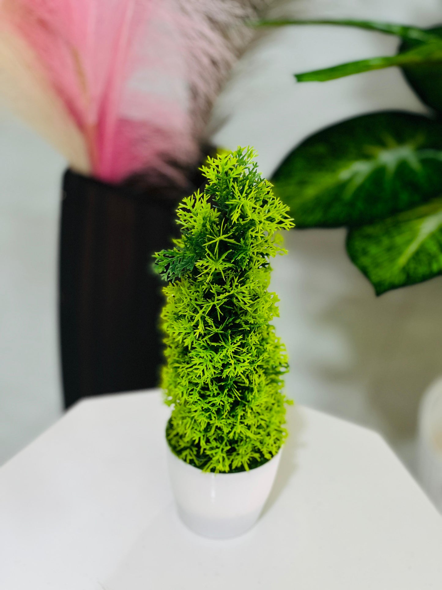 Artificial green tree in a white pot with a blurred background